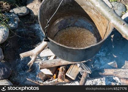 Cooking over a campfire. Camping fire and kettle with food