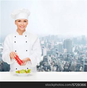 cooking, people and food concept - smiling female chef spicing vegetable salad over city background