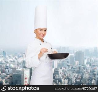 cooking, people and food concept - smiling female chef with pan and spoon mixing food over city background