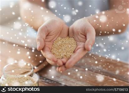 cooking, people and home concept - close up of male cupped hands with quinoa in kitchen