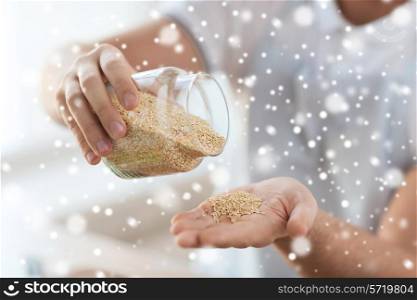 cooking, people and home concept - close up of male emptying jar with quinoa