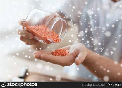 cooking, people and home concept - close up of man emptying jar with red lentils in kitchen