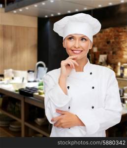 cooking, people, bakery and food concept - smiling female chef, cook or baker dreaming over restaurant kitchen background