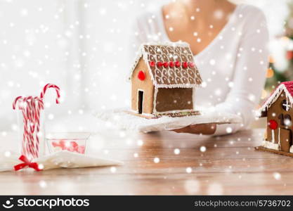 cooking, people, christmas and baking concept - close up of happy woman holding and showing gingerbread house at home