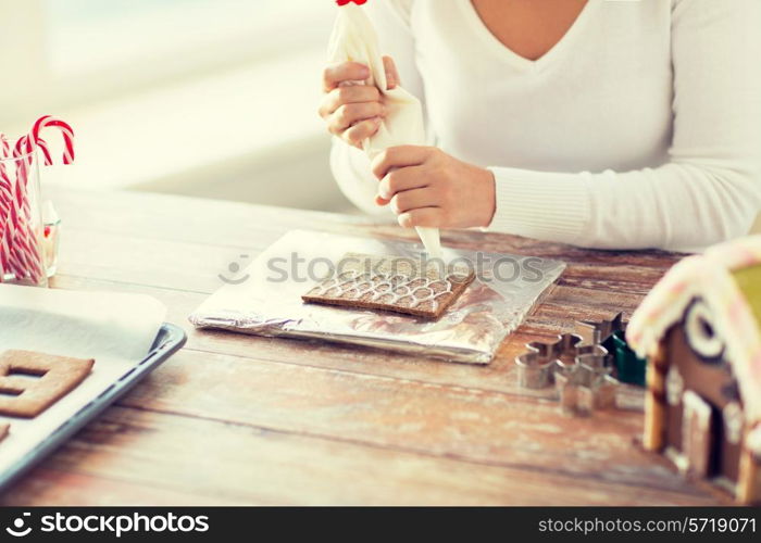 cooking, people, christmas and decoration concept - close up of happy woman making gingerbread houses at home