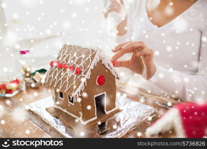 cooking, people, christmas and decoration concept - close up of happy woman making gingerbread houses at home