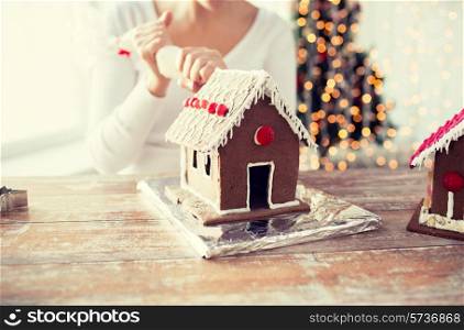 cooking, people, christmas and decoration concept - close up of happy woman making gingerbread houses at home