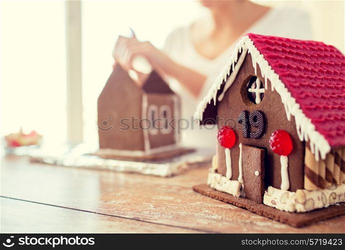 cooking, people, christmas and decoration concept - happy woman making gingerbread houses at home