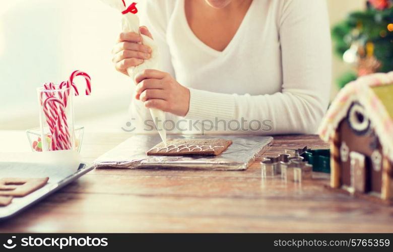 cooking, people, christmas and decoration concept - happy woman making gingerbread houses at home