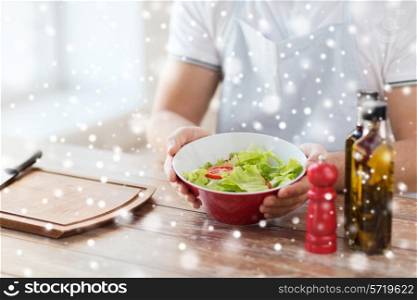 cooking, people, food, vegetarian and home concept - close of male hands holding bowl with salad in kitchen