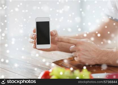 cooking, people, technology and home concept - close up of man with vegetables on table showing blank smartphone screen in kitchen