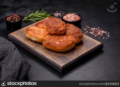 Cooking pies with potato on a wooden cutting board on a black background. Cooking pies with potato on a wooden cutting board