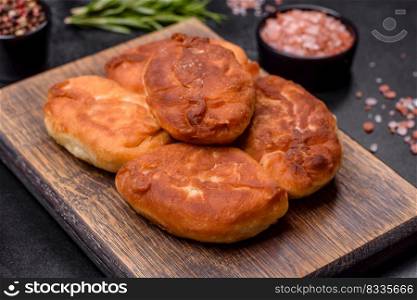 Cooking pies with potato on a wooden cutting board on a black background. Cooking pies with potato on a wooden cutting board