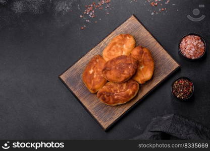 Cooking pies with potato on a wooden cutting board on a black background. Cooking pies with potato on a wooden cutting board