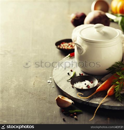 Cooking pot and vegetables for making vegetable soup on rustic background