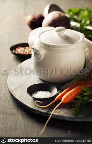 Cooking pot and vegetables for making vegetable soup on rustic background
