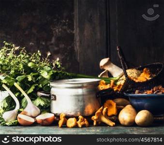 Cooking pot, forest mushrooms and cooking ingredients for soup or stew on dark rustic kitchen table at wooden background, side view, border