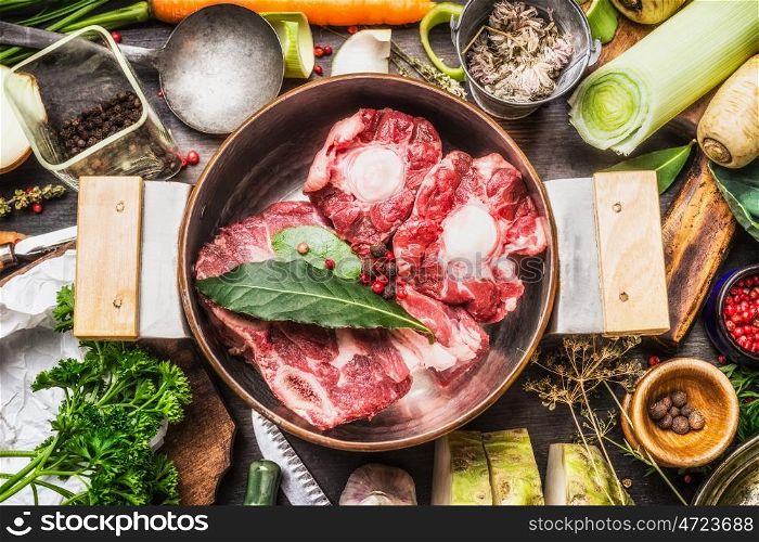 Cooking pot with soup or bone broth meat and vegetables cooking ingredients and spices on kitchen table, top view
