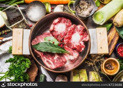 Cooking pot with soup or bone broth meat and vegetables cooking ingredients and spices on kitchen table, top view