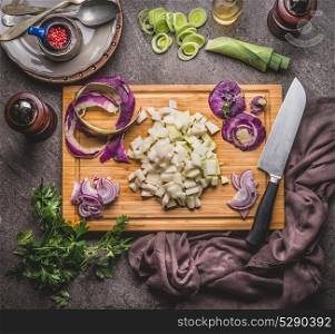 Cooking preparation with vegetables: kohlrabi and leeks on wooden cutting board with knife on rustic background, top view. Healthy vegetarian food and eating, clean or diet nutrition concept