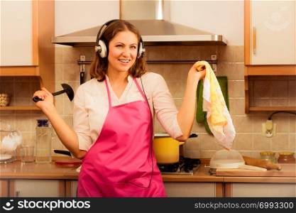 Cooking preparing and making food concept. Modern beauty woman housewife cook chef wearing pink apron listening music on earphones singing and dancing in kitchen.. Crazy housewife cook in kitchen