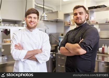 cooking, profession and people concept - happy male chef and cook at restaurant kitchen. happy smiling chef and cook at restaurant kitchen