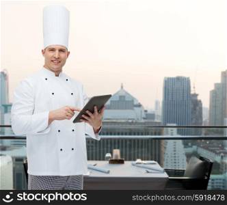cooking, profession and people concept - happy male chef cook holding tablet pc computer over city restaurant lounge background
