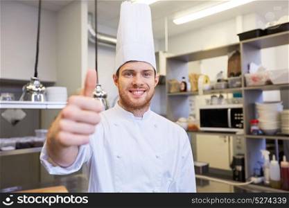 cooking, profession and people concept - happy male chef cook in toque at restaurant kitchen showing thumbs up. happy chef at restaurant kitchen showing thumbs up
