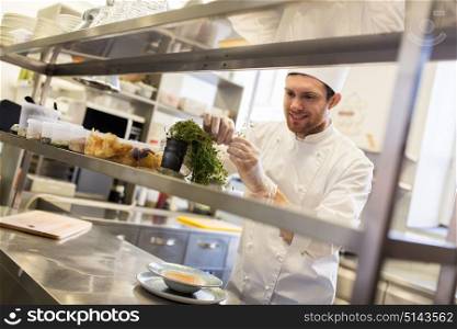 cooking, profession and people concept - happy male chef cook making food at restaurant kitchen. happy male chef cooking at restaurant kitchen