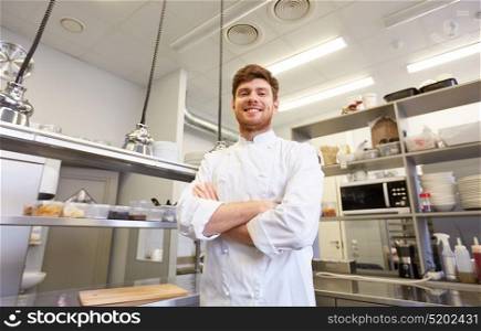 cooking, profession and people concept - happy male chef cook with crossed hands at restaurant kitchen. happy male chef cook at restaurant kitchen
