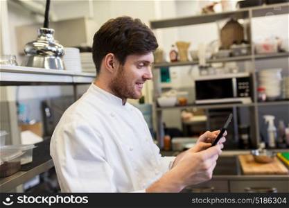 cooking, profession and people concept - happy male chef cook with tablet pc computer at restaurant kitchen. chef cook with tablet pc at restaurant kitchen