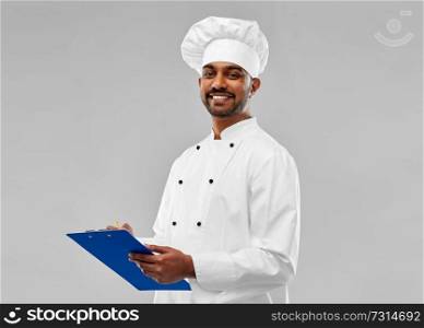 cooking, profession and people concept - happy male indian chef in toque with clipboard over grey background. happy male indian chef in toque with clipboard