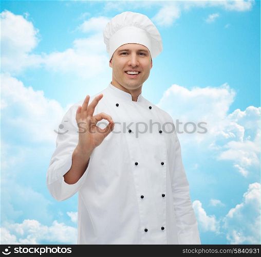 cooking, profession, gesture and people concept - happy male chef cook showing ok sign over blue sky with clouds background
