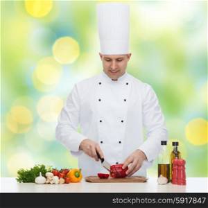cooking, profession, vegetarian, food and people concept - happy male chef chopping pepper over green lights background