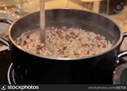 Cooking Rice with Tomato in Black Saucepan with Wooden Ladle