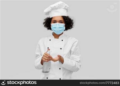 cooking, safety and health concept - female chef in protective medical mask and toque with hand sanitizer or liquid soap over grey background. female chef in mask with hand sanitizer or soap