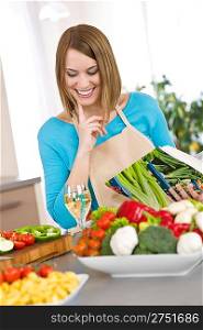 Cooking - Smiling woman holding cookbook in modern kitchen, with vegetable and pasta