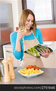 Cooking - Smiling woman reading recipe from cookbook, Italian pasta and vegetable