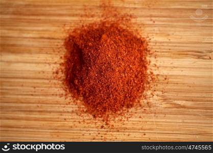 cooking, spice and ethnoscience concept - cayenne, chili pepper or paprika powder on wood