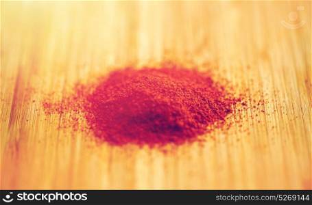 cooking, spice and ethnoscience concept - cayenne, chili pepper or paprika powder on wood. cayenne pepper or paprika powder on wood