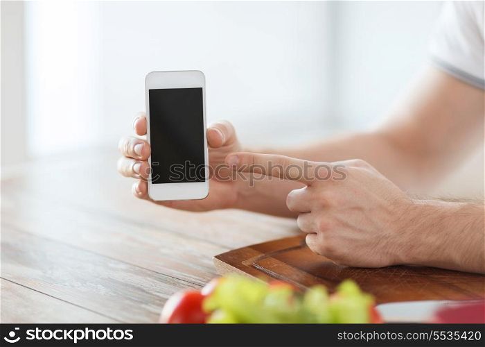 cooking, technology, advertising and home concept - close up of male hands holding smartphone with blank black screen