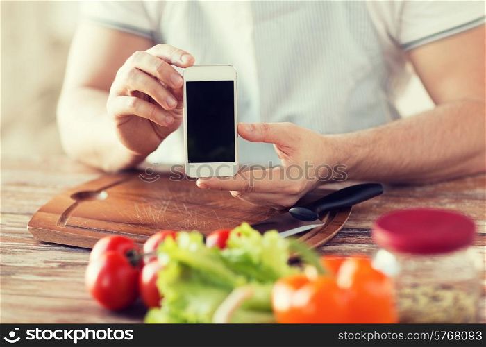 cooking, technology, advertising and home concept - close up of male hands holding smartphone with blank black screen