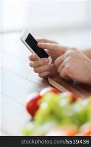 cooking, technology and home concept - closeup of male hand pointing finger to smartphone