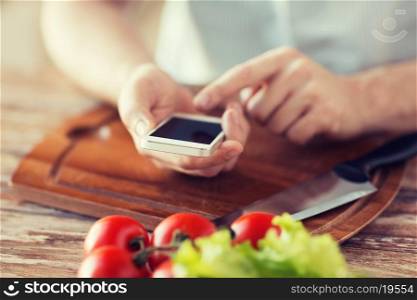 cooking, technology and home concept - closeup of man pointing finger to smartphone