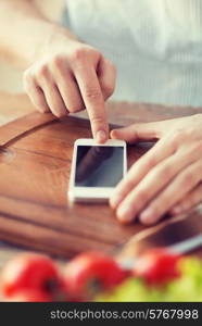 cooking, technology and home concept - closeup of man pointing finger to smartphone