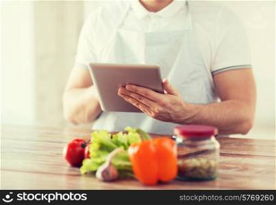 cooking, technology and home concept - closeup of man reading recipe from tablet pc computer