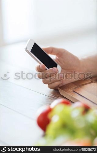 cooking, technology and home concept - closeup of man with smartphone