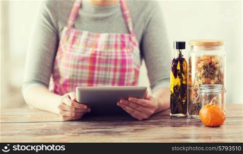 cooking, technology and home concept - closeup of woman reading recipe from tablet pc computer