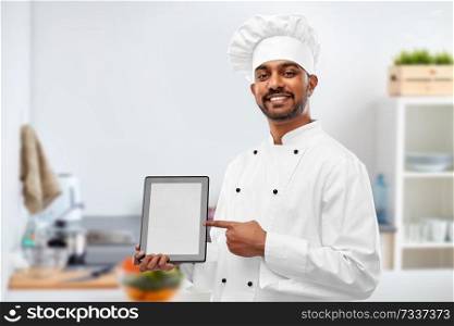 cooking, technology and people concept - happy male indian chef in toque with tablet computer over kitchen background. happy indian chef with tablet computer at kitchen