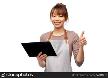 cooking, technology and people concept - happy smiling female chef or waitress in apron with tablet pc computer showing thumbs up over white background. happy woman in apron with tablet pc computer